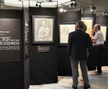 People viewing portraits at the Faces Beyond Homelessness exhibit