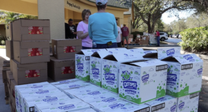 Volunteers standing near stacks of boxes filled with donated food