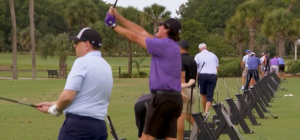 A row of golfers practicing their swings at the driving range during the St. Matthew's House Charity Golf Scramble