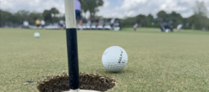 A golf ball near the cup and flag pole on the putting green at the St. Matthew's House Charity Golf Scramble